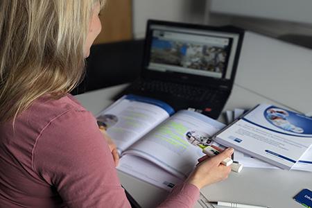 Person mit Laptop und Buch